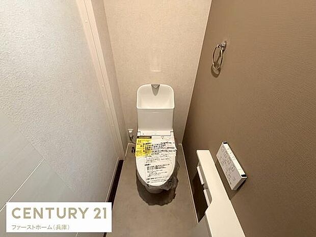 シンプルなデザインで清潔感のあるトイレです。壁面には便利なペーパーホルダーを設置。落ち着いた色合いの内装が特徴です。操作しやすいリモコンも備え付けられています。スペースも確保されており快適な印象です。