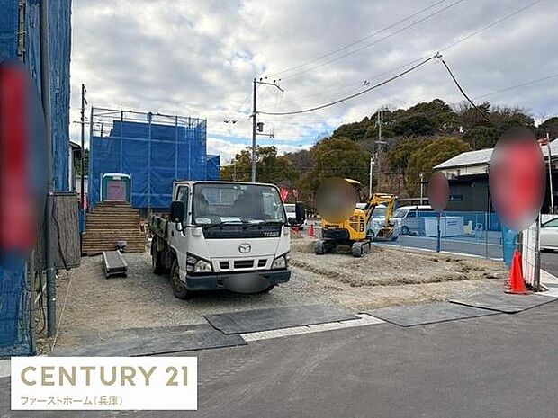 建築中の現場がしっかり確認できる写真です。周囲には落ち着いた住宅街が広がっています。重機やトラックも写っており現場の進行状況がよくわかります。道路に面した立地でアクセスも便利です。