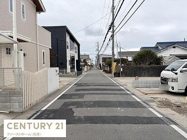 前面道路はすっきりと整備されており車の通行も安心です。周囲には住宅が並び落ち着いた雰囲気が広がっています。電柱や配線がきれいに配置されているため街並みが整っています。