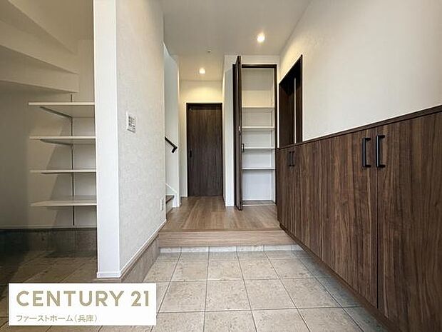 玄関には広々とした収納スペースが備わっておりすっきりとした印象です。明るい照明が玄関全体を照らしています。木目調の建具が落ち着いた雰囲気を演出します。