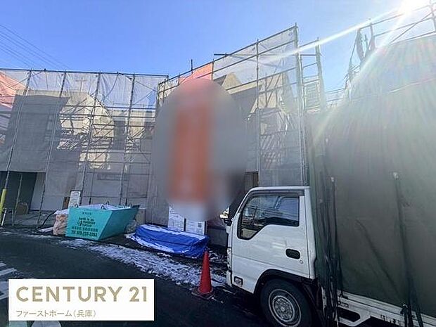 建築中の現場の様子がご覧いただけます。足場やシートが設置されておりしっかりとした施工体制が伝わります。青空の下現場の雰囲気も明るく広がります。工事用車両や資材も整理されており現場が整然としています。