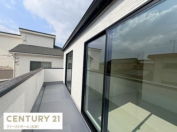 開放感のあるワイドなバルコニーです。ガラス戸から光が差し込み明るい空間を演出します。近隣の住宅との程よい距離感もポイントです。壁や床のカラーが統一されていてすっきりとした印象を受けます。