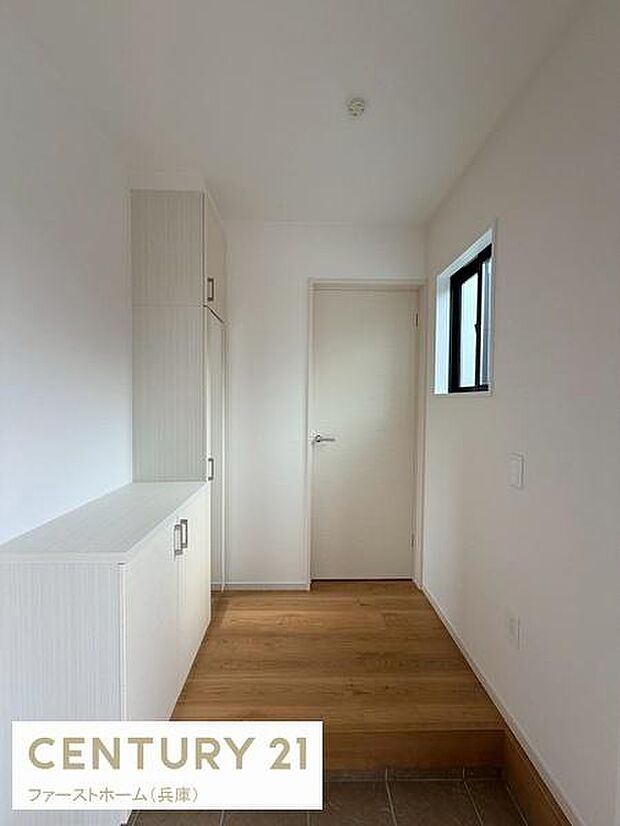 明るい採光が魅力の玄関です。収納が備わっておりすっきりとした空間となっています。ナチュラルな色合いの床と壁が印象的です。シンプルで使いやすい玄関スペースです。アクセントとなる窓が配置されています。