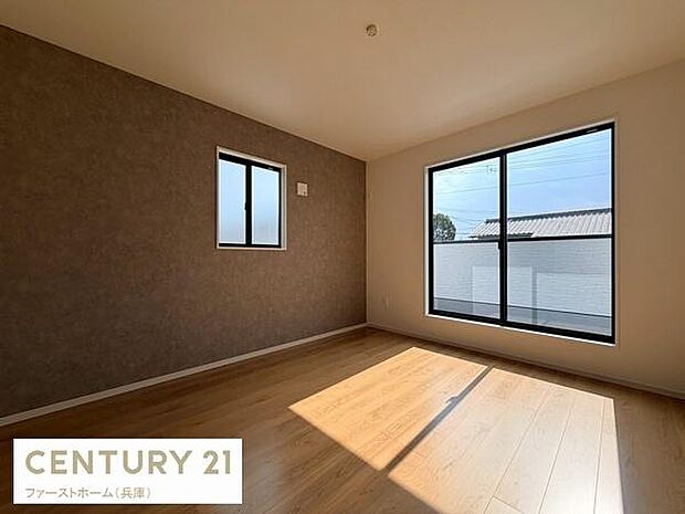 大きな窓から自然光が差し込む寝室です。壁のアクセントカラーが落ち着いた雰囲気を演出しています。床は木目調で清潔感のある空間です。窓が2面にあり換気もしやすく快適です。