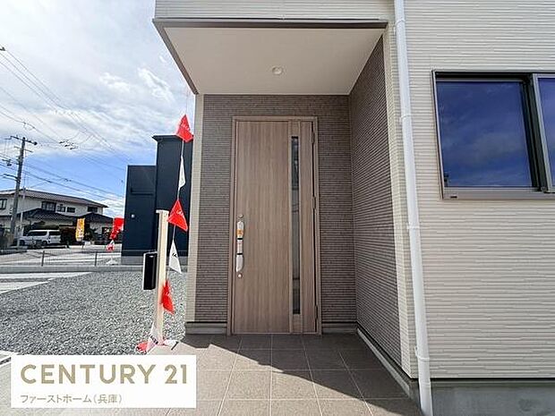 玄関はゆとりあるスペースで明るい雰囲気が広がります。外観と調和したデザインが目を惹きます。雨の日も安心の屋根付きです。玄関前のタイル張りが清潔感を演出します。シンプルで落ち着いた印象が特徴です。