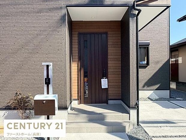 落ち着いた色合いの外壁が特徴の玄関です。清潔感のあるアプローチが出迎えます。広めの玄関スペースが開放感を演出します。シンプルなデザインが印象的です。郵便ポストも使いやすそうです。