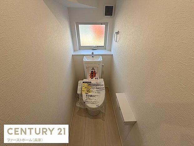 窓付きのトイレで明るさを感じられます。シンプルで使いやすいデザインです。スペースが確保されており清潔感のある内装です。ペーパーホルダーや換気設備も設置されています。