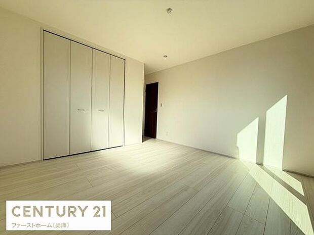 シンプルな内装で清潔感のある寝室です。大きな窓から差し込む自然光が明るさを演出しています。クローゼット付きで収納スペースも確保されています。床材の質感が部屋全体に落ち着きを与えています。