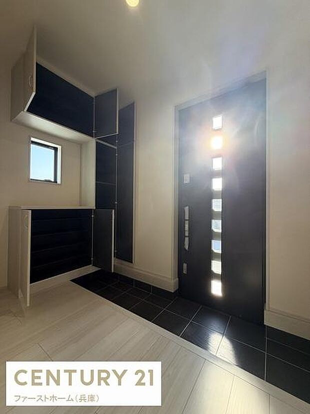 玄関ドアのデザインが印象的です。収納スペースが充実しており整理整頓しやすい仕様です。窓からの自然光が玄関を明るく演出します。タイル床がアクセントになっています。