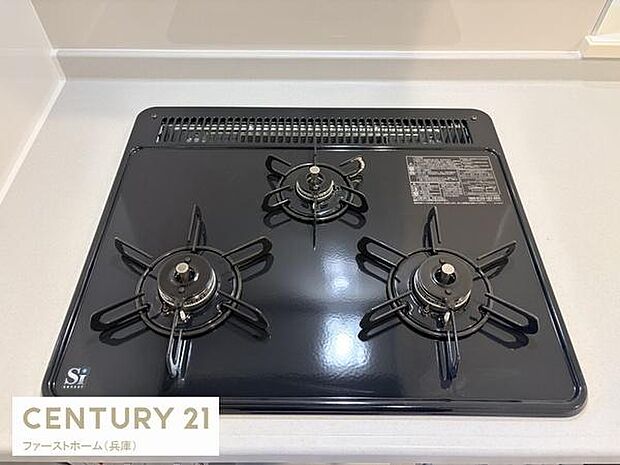 清潔感のあるキッチンに設置された三口ガスコンロです。使いやすさを重視したシンプルなデザインが特徴です。お手入れのしやすいフラットな天板仕様です。ゆとりある調理スペースが確保されています。