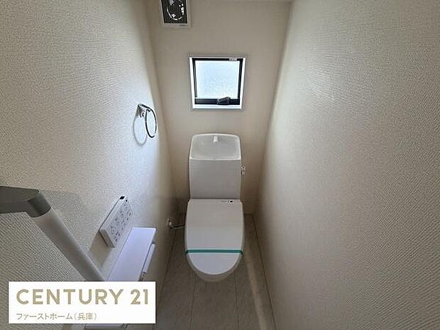 シンプルで使いやすいデザインのトイレです。小窓があるため明るい空間が確保されています。壁の色合いが落ち着いた雰囲気を演出しています。ペーパーホルダーやタオルリングも使いやすい位置に設置されています。