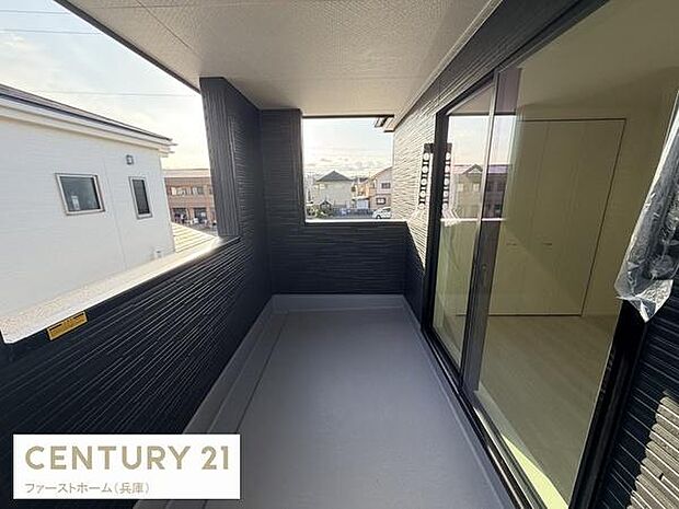 ゆったりとしたスペースが確保されたバルコニーです。屋根付きで天候の影響を受けにくい造りになっています。大きな窓から室内へ自然光が差し込みます。周辺の住宅も見渡せる開放感があります。