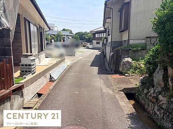 前面道路が舗装されており車両の通行がしやすい環境です。周辺には住宅が並んでいて落ち着いた雰囲気です。現地写真から建物の外観や道路の幅を確認することができます。見通しの良い前面道路が印象的です。