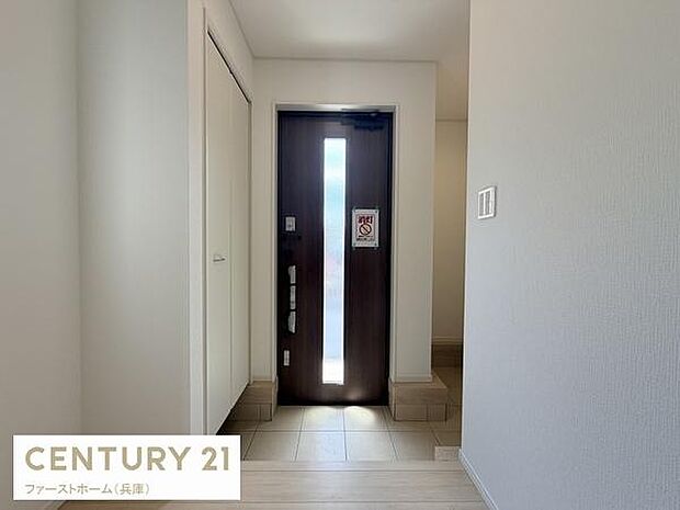 明るい玄関がシンプルですっきりとした印象を与えます。大きなドアガラスが採光性を高めています。白を基調とした壁が清潔感を演出します。玄関収納スペースも確保されています。使い勝手の良い配置が特徴です。