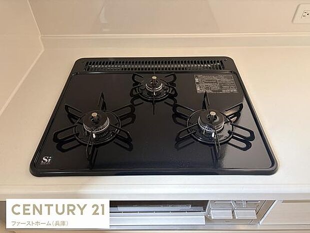 シンプルなデザインの三口コンロが設置されており調理スペースがすっきりしています。清潔感のあるキッチン周りで手入れもしやすそうです。キッチンの使い勝手の良さが感じられるポイントです。