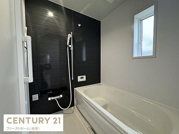 浴室にはシンプルなデザインが施されています。壁面のアクセントカラーが空間を引き締めます。大きめの窓が設けられ換気にも配慮されています。バスタブとシャワーの設備が整っています。