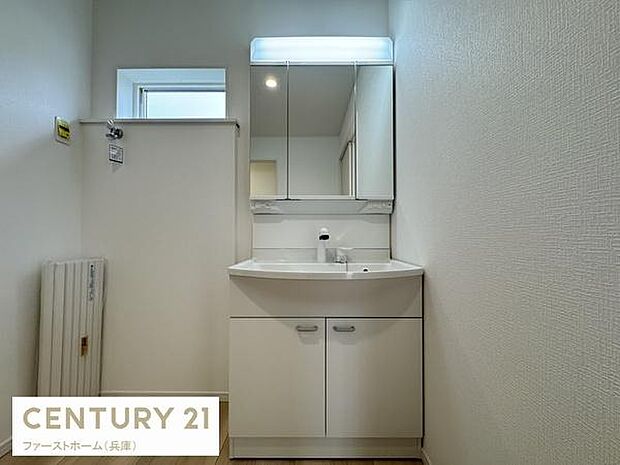 清潔感のある洗面台が配置され鏡の収納も備わっています。すっきりとしたデザインで空間が広く見えます。明るい照明が備えられており使い勝手にも配慮されています。窓があるため換気も行いやすい洗面所です。