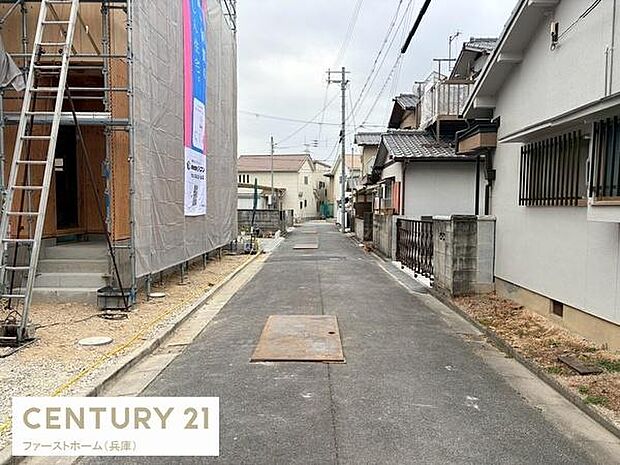 現地の前面道路は舗装されており落ち着いた雰囲気が感じられます。建物の外観や周囲の住宅も確認でき周辺の様子も一目でわかります。