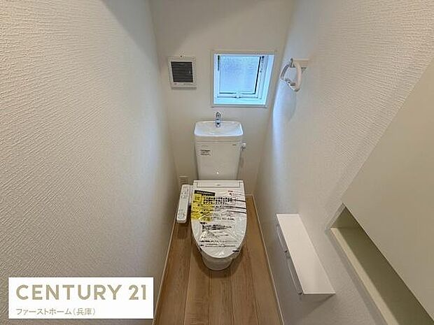 小窓が設けられており換気がしやすいトイレです。清潔感のある白を基調とした内装です。温水洗浄便座が備え付けられています。木目調の床があたたかみを感じさせます。ペーパーホルダーも設置されています。