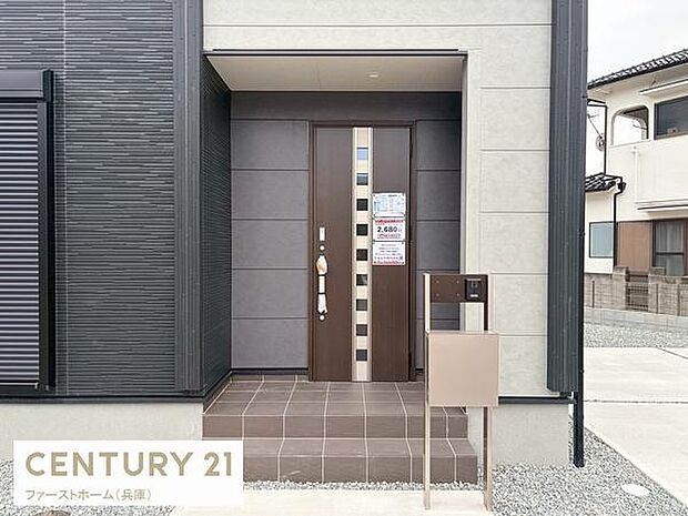 シンプルでモダンな玄関が印象的です。ダークカラーの扉が外観に調和しています。郵便受けやインターホンも設置されています。屋根付きで雨の日も安心できます。エントランスが広く出入りがしやすいです。