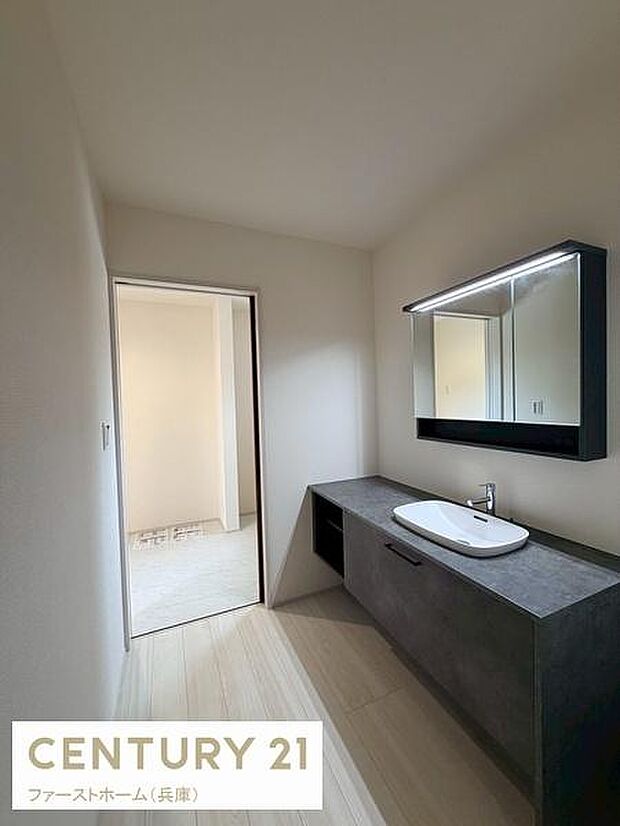 シンプルで落ち着いた印象の洗面台が空間をすっきりと見せています。広めのカウンターで使い勝手も良好です。鏡の上部には照明が設置されており作業がしやすくなっています。収納スペースも確保されています。