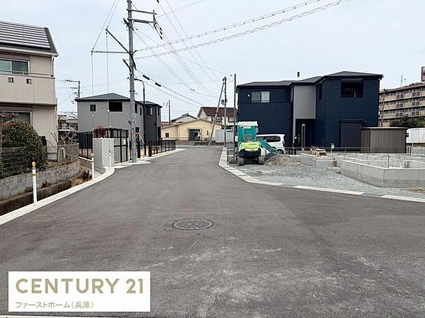 前面道路が広く車の出し入れがしやすい環境です。周辺は新しい建物が多く整った街並みが特徴です。車両の通行もゆとりが感じられる現地写真です。全体的に落ち着いた雰囲気にまとまっています。