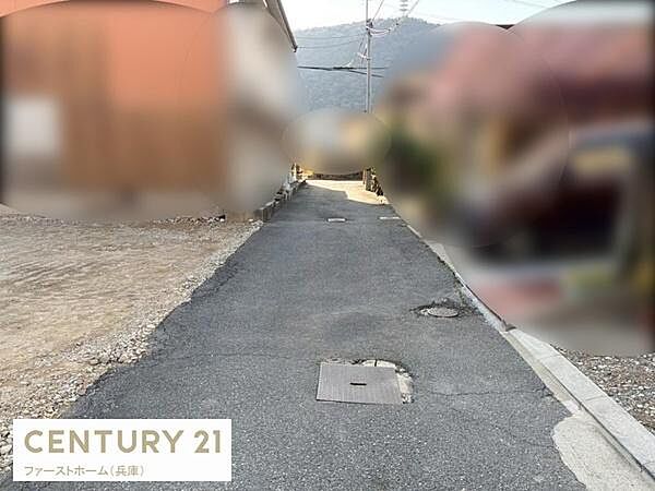 現地の前面道路は舗装されており落ち着いた雰囲気が感じられます。建物の外観や周囲の住宅も確認でき周辺の様子も一目でわかります。
