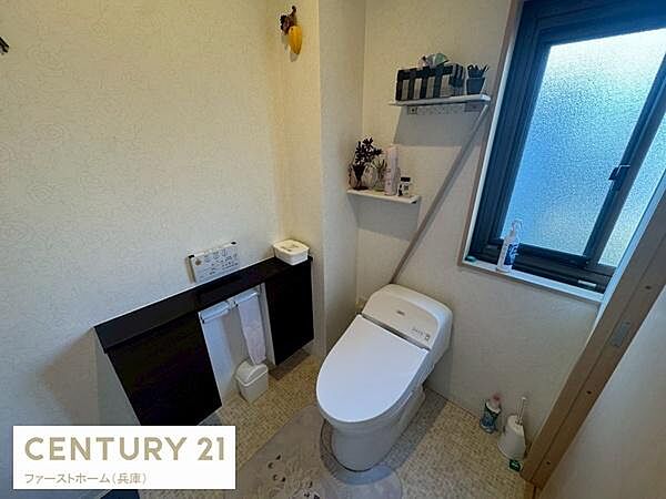 窓付きで自然光が入りやすいトイレです。収納棚があり小物や備品の整理もしやすい空間になっています。手洗い場も設けられ機能的な設計です。清潔感のある内装で使い勝手にも配慮されています。