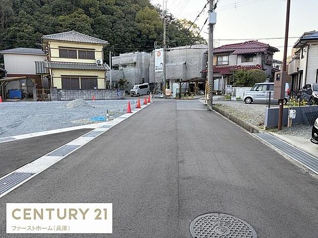 現地の前面道路は舗装されており落ち着いた雰囲気が感じられます。建物の外観や周囲の住宅も確認でき周辺の様子も一目でわかります。