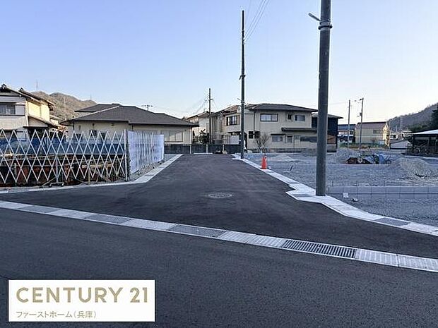 現地の前面道路は舗装されており落ち着いた雰囲気が感じられます。建物の外観や周囲の住宅も確認でき周辺の様子も一目でわかります。