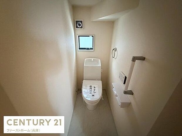 トイレには小窓があり明るい自然光が入ります。手すりも設置されており使いやすさに配慮されています。壁面にはペーパーホルダーやリモコンが設置され機能性も備えています。清潔感のある空間です。