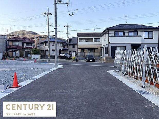 現地の前面道路は舗装されており落ち着いた雰囲気が感じられます。建物の外観や周囲の住宅も確認でき周辺の様子も一目でわかります。