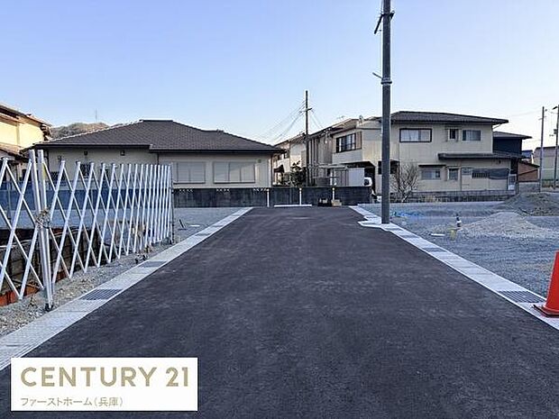 現地の前面道路は舗装されており落ち着いた雰囲気が感じられます。建物の外観や周囲の住宅も確認でき周辺の様子も一目でわかります。