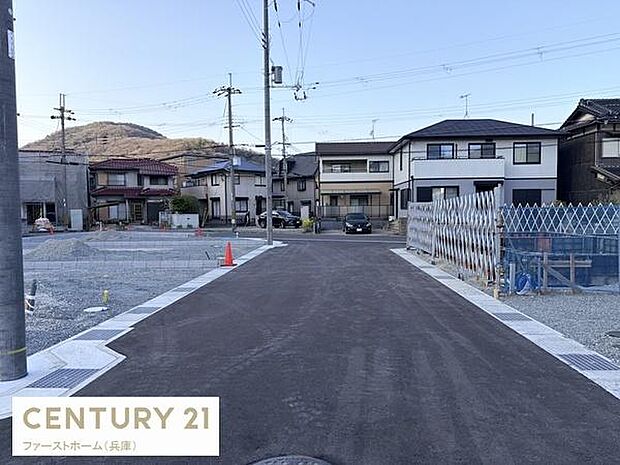 現地の前面道路は舗装されており落ち着いた雰囲気が感じられます。建物の外観や周囲の住宅も確認でき周辺の様子も一目でわかります。