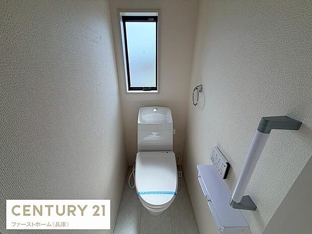 窓付きで明るさを感じられるトイレです。シンプルな内装で清潔感があります。棚やペーパーホルダーも備わっており使いやすい設計です。壁付きリモコンで操作も快適に行えます。