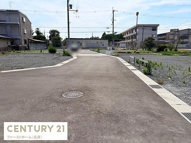 前面道路が広く車の出し入れもしやすい現地写真です。周辺には余裕のあるスペースが広がっています。ゆったりとした道路設計が印象的です。敷地全体の様子が分かりやすく撮影されています。