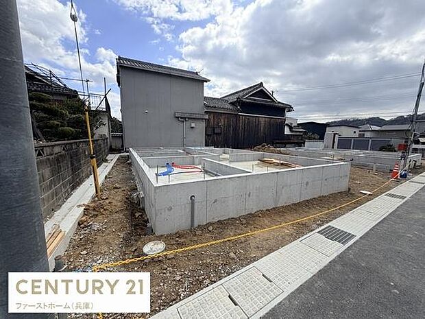 新築住宅の基礎工事が進行中の様子です。周囲には落ち着いた住宅が立ち並び静かな環境が感じられます。しっかりとした基礎構造で建築の安心感が伝わります。道路に面した位置も特徴的です。