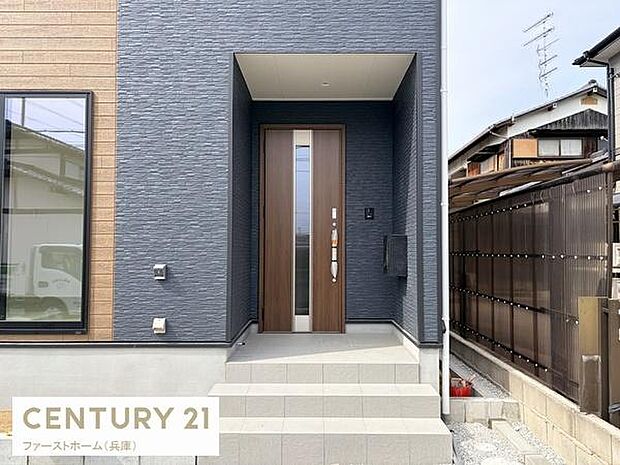 モダンな外観が印象的な玄関です。シンプルなデザインで清潔感のあるアプローチになっています。段差の少ないフラットな玄関まわりが特徴です。扉周辺の配色が美しく調和しています。