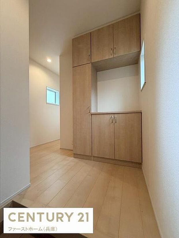 木目調の収納が印象的な玄関です。明るい色合いの床が空間全体をやわらかく演出しています。小窓が設けられているため自然な明るさを感じられます。収納スペースがしっかり確保されています。