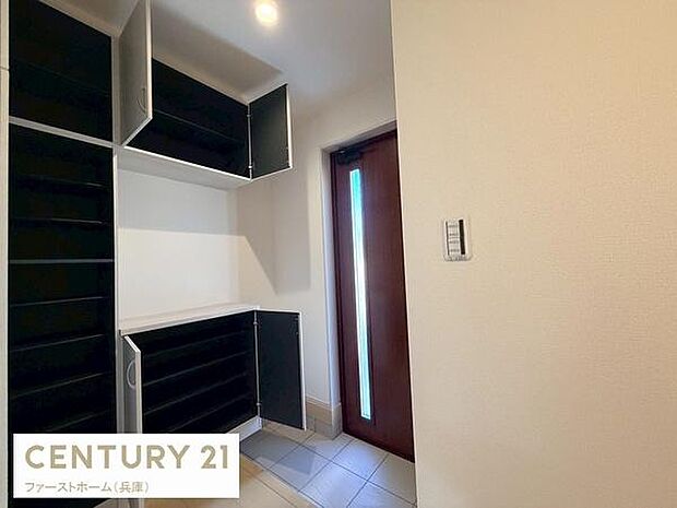 玄関にはたっぷり収納できるシューズボックスが設置されています。明るい採光のあるドアが魅力的です。すっきりとした白い壁で清潔感があります。床にはお手入れしやすいタイルが採用されています。