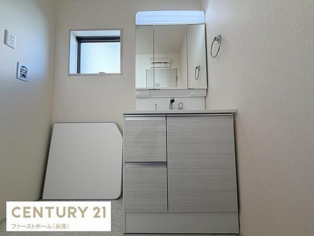 清潔感のある洗面台が設置されています。窓があり換気しやすい点が特徴です。収納スペースも確保されており物の整理がしやすい仕様です。ミラー部分には明るい照明があり使い勝手が良いです。