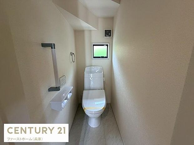 トイレには窓があり自然光が感じられる空間です。壁側には手すりが設置されていて安心感が得られます。収納棚やペーパーホルダーも設けられ使いやすいレイアウトです。