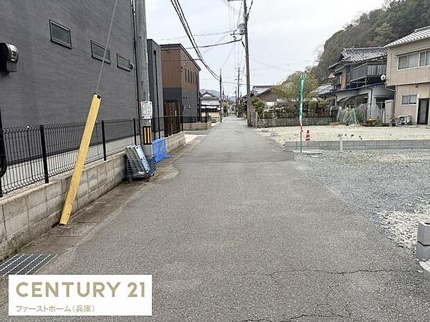 現地の前面道路は舗装されており落ち着いた雰囲気が感じられます。建物の外観や周囲の住宅も確認でき周辺の様子も一目でわかります。