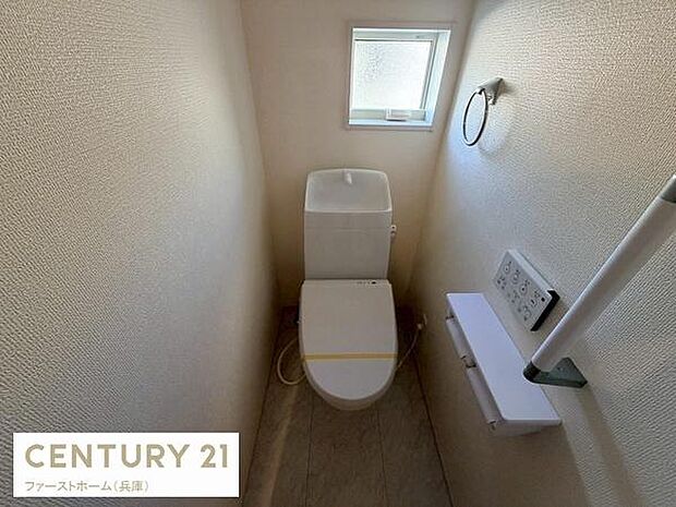 コンパクトな空間に手洗い付きトイレを設置しています。窓があり換気しやすい設計です。便利なペーパーホルダーや操作パネルも備わっています。壁面の質感も特徴的です。