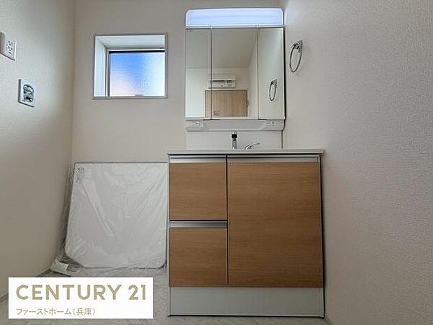 洗面台はゆったりとしたサイズ感が魅力的です。鏡面は収納付きで整理整頓がしやすい仕様です。ナチュラルな木目調が空間に調和しています。窓があり自然光が差し込む明るい空間です。