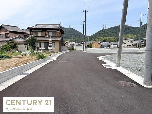 前面道路は広々としており車の出し入れもしやすい現地土地写真です。周囲には住宅が並び落ち着いた環境が広がっています。電柱や歩道も整備されていてすっきりとした街並みが確認できます。
