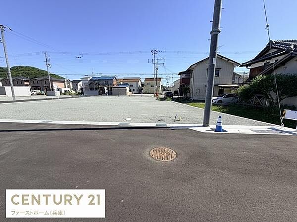広々とした現地土地写真です。道路幅も十分に確保されており周囲には住宅が立ち並ぶエリアです。平坦な地形が特徴的で整備された街並みが感じられます。開放的な雰囲気が魅力の一角です。