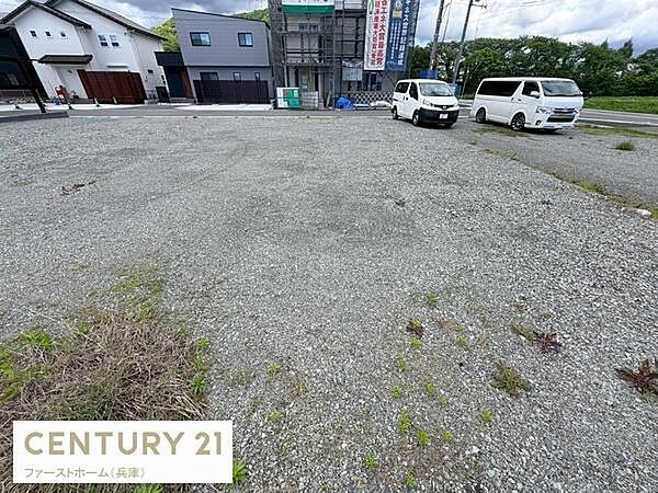 現地土地写真は広々としたスペースが特徴です。道路に面しており周辺には住宅や建築中の建物も見られます。敷地内は整地されており車の進入もしやすい状況です。周囲の環境も落ち着いた雰囲気となっています。