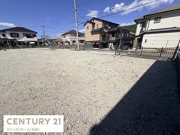 住宅街の一画に位置する現地土地写真です。周囲には落ち着いた住宅が建ち並び前面道路も広々としています。すっきりとした形状で利用しやすい土地となっています。日当たりも期待できる明るい印象の現地です。