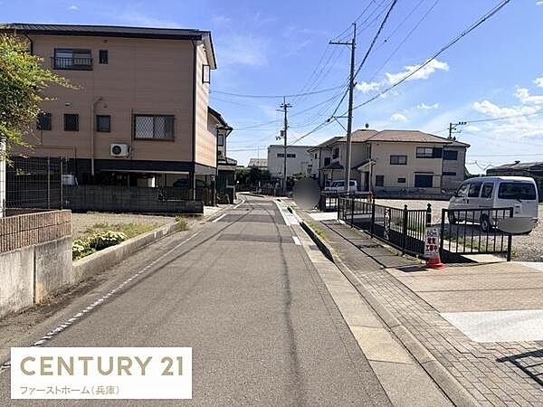 前面道路が広々としており車の出入りもスムーズに行えます。周囲には住宅が立ち並び落ち着いた雰囲気が感じられます。電柱や歩道も整備されていて日当たりも良好な現地写真です。